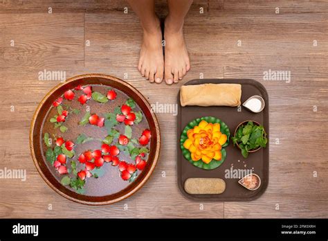 Closeup Shot Of A Woman Feet Dipped In Water With Petals In A Wooden