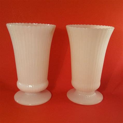 Two White Vases Sitting Side By Side On A Red Surface