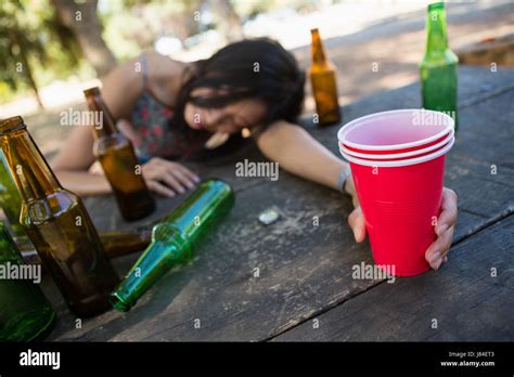 Mujer Borracha Durmiendo En La Mesa Y Sosteniendo Un Vaso De Cerveza En El Parque Fotografía De