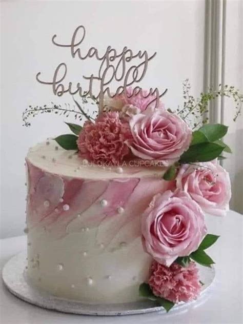 A Birthday Cake Decorated With Pink Flowers And Greenery