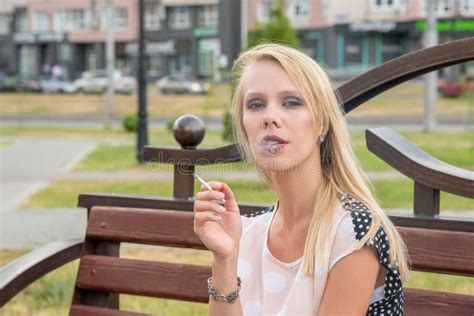 beautiful blonde girl smokes a white cigarette outdoors in a cit stock image image of beauty