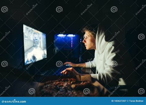 Concentrated Young Gamer Playing Video Games On A Computer With A Pizza