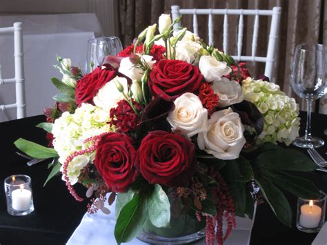 A Vase Filled With Red And White Flowers Sitting On Top Of A Table Next