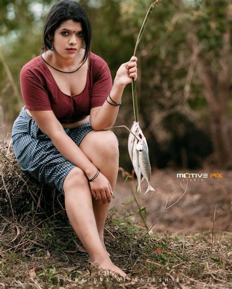 A Woman Is Sitting On The Ground With A Fish In Her Hand And Looking At The Camera