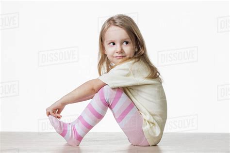 Side View Of Cute Girl Sitting On Floor Against White Background