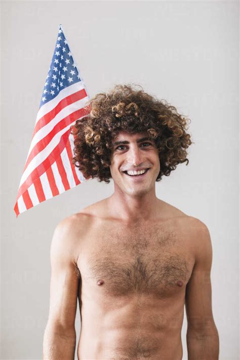 Portrait Of Naked Man With Curly Hair In Front Of American Flag Stock Photo