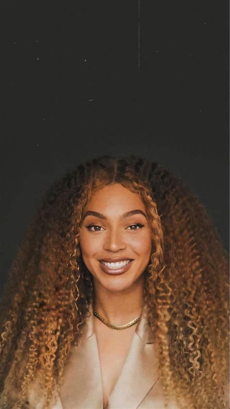 A Woman With Long Curly Hair Smiling At The Camera