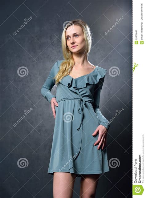 Skinny Blonde Girl In Gray Dress On The Background Of Gray Wall Stock