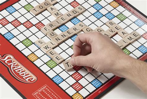 A Scrabble Board Game Being Played By Someones Hand