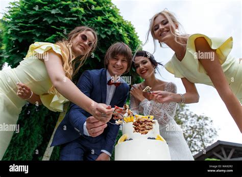 Newlyweds And Bridesmaids Have Fun And Eat Wedding Cake Together In The
