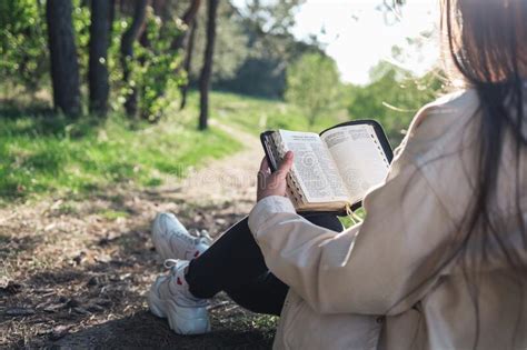 christian woman holds bible in her hands reading the holy bible in a field during beautiful