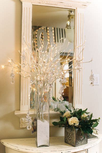 On An Entryway Table A Vase Filled With Lighted Branches And Crystal
