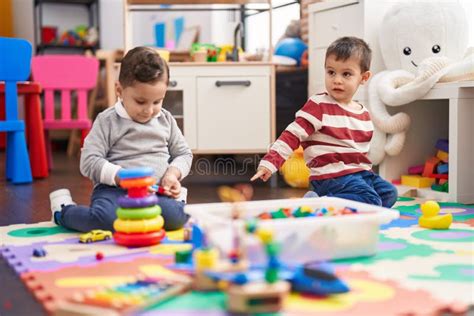 Two Kids Playing With Toys Sitting On Floor At Kindergarten Stock Image