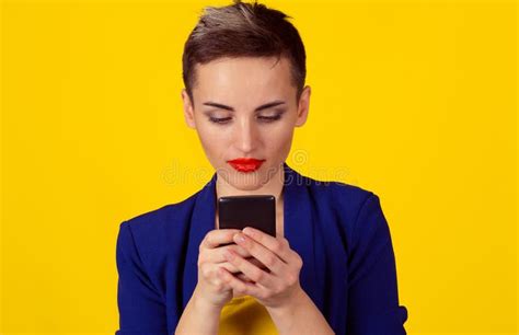 serious business woman looking texting at phone isolated yellow background wall short hair