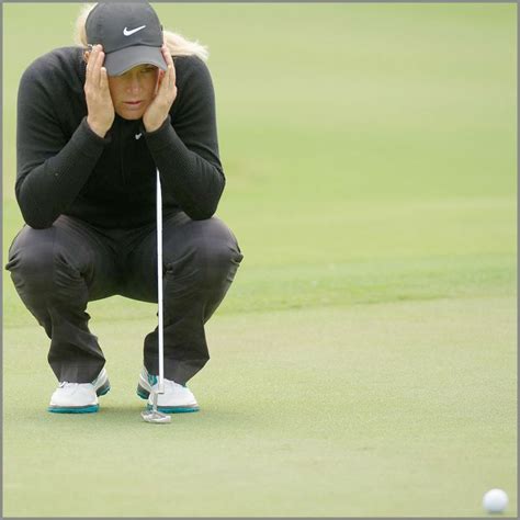 A Woman Kneeling Down On Top Of A Green Next To A Golf Ball