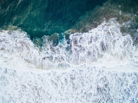 An Overhead Drone Shot Of Foam And Ripples In The Dark Blue Ocean