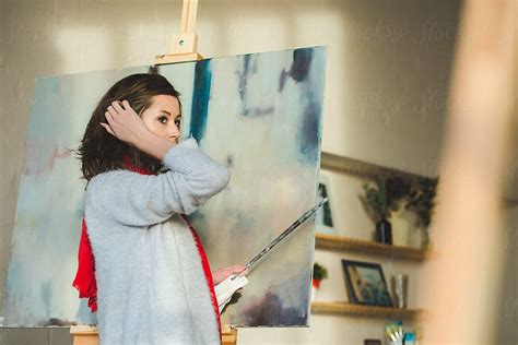 Portrait Of Beautiful Female Artist Standing Against Paintings In