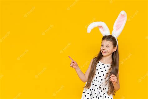 Premium Photo A Beautiful Girl In An Easter Bunny Costume Points At The Advertisement And Smiles