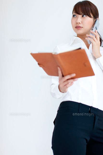 携帯電話で話しながら手帳を持っているビジネスウーマン[07800011451]の写真素材・イラスト素材｜アマナイメージズ