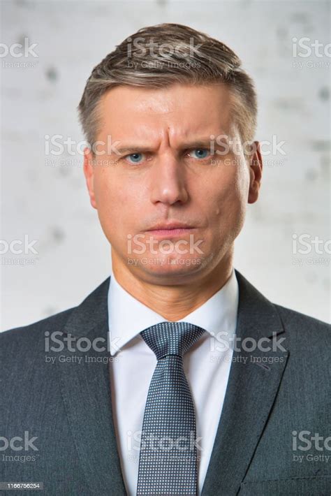 Portrait Of Angry Businessman Standing Against Wall Stock Photo