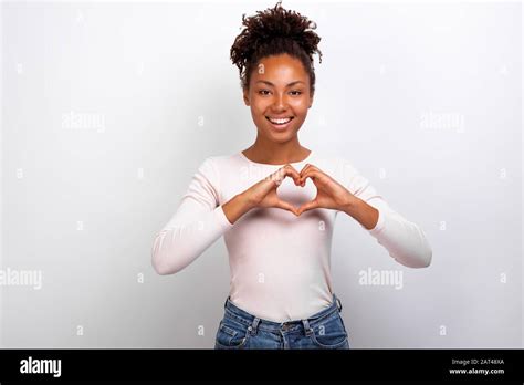 cute mulatto woman shows a heart gesture with her fingers next her chest concept gesture