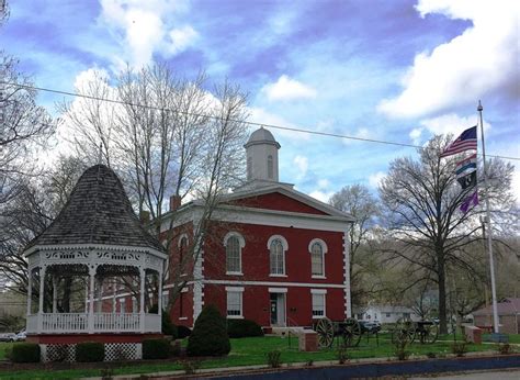An Old Red Brick Building With A White Gazebo And American Flag On The