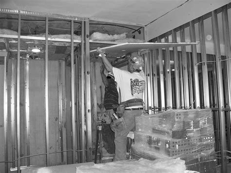 Average cost to drywall a basement ceiling: Ceiling drywall panel installation Installers are shown ...