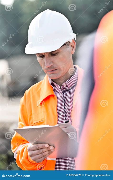 Supervisor Writing On Clipboard At Construction Site Stock Image