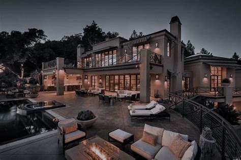An Outdoor Living Area With Couches And Fire Pit In Front Of A Large House
