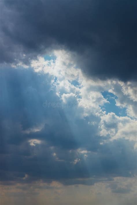 Heavenly Sun Rays Through Dark Clouds Against The Blue Sky Stock Image