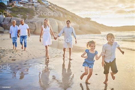 다세대 가족이 손을 잡고 함께 해변을 따라 걷습니다 여름 휴가를 즐기는 두 자녀 두 명의 부모와 조부모가있는 백인 가족 노인에