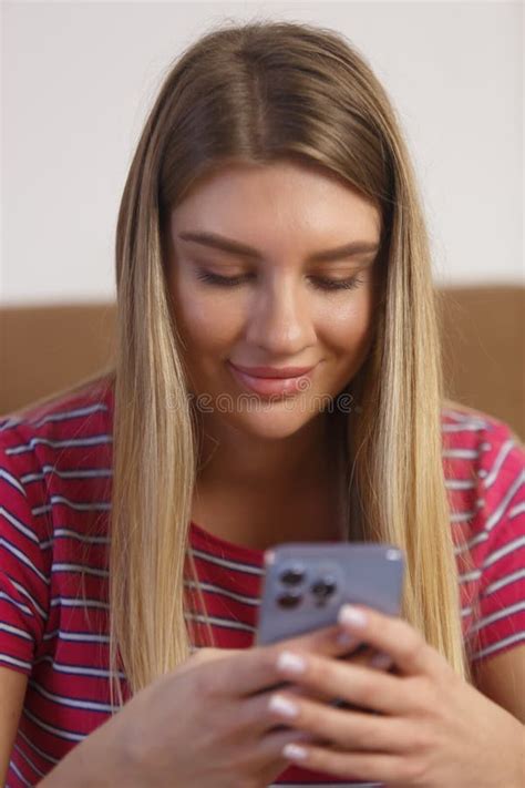 Portrait Of Beautiful Blonde Girl Typing A Message On Mobile Phone