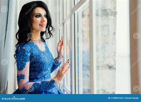 Beautiful Brunette In A Blue Dress At A Wide Window A Woman In A Chic