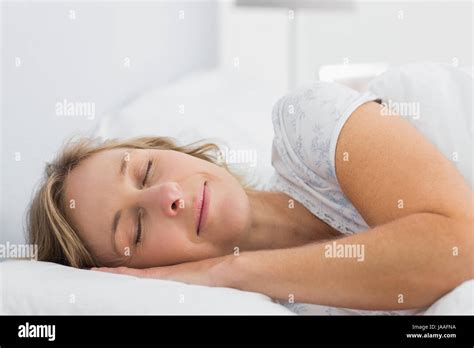 Peaceful Blonde Woman Sleeping In Bed At Home In Bedroom Stock Photo