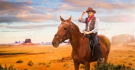 Cowboy riding a horse in desert valley, western - stock photo 1455689