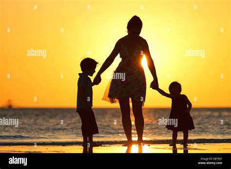 Silhouettes d une mère et ses deux enfants sur la plage au coucher du soleil Photo Stock Alamy