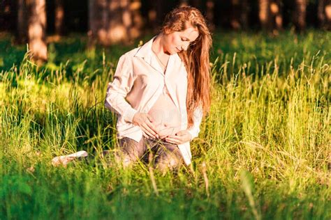 A Pregnant Woman Sits On The Edge Of The Forest In The Rays Of The Evening Sun Stock Image