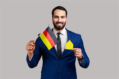 Satisfied Man Holding German Flag And Paper House Dreaming To Buy His
