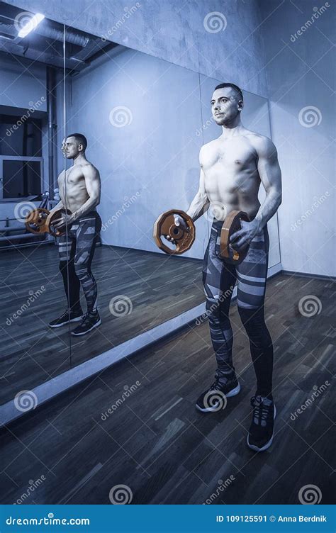 muskulöse bodybuildermänner die Übungen im nackten torso der turnhalle tun getontes bild