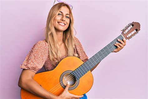 Beautiful Blonde Young Woman Playing Classical Guitar Smiling And