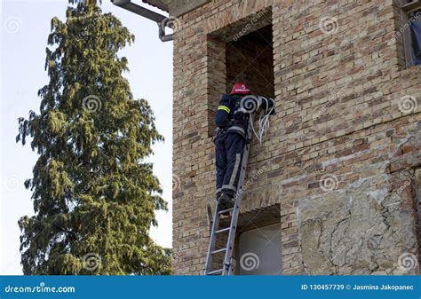 Firefighter On Duty Climbs The Ladder To Enter The Window Stock Image