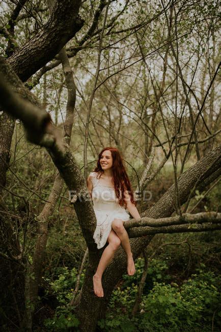 Ginger Girl Posing On Bending Over Ground Tree Branch And Looking Aside