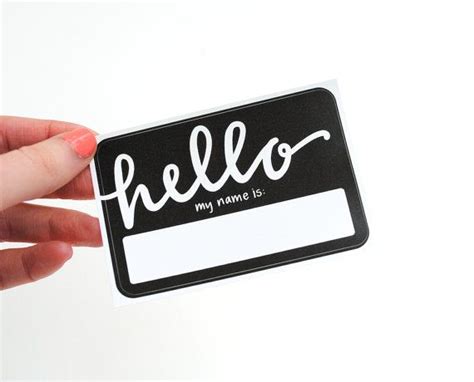 A Hand Holding A Black And White Hello Name Tag