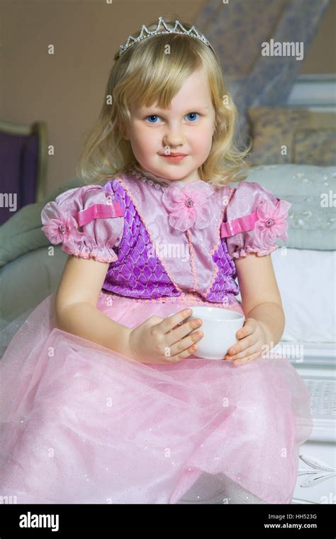Little Happy Princess Girl In Pink Dress And Crown In Her Royal Room Posing And Smiling Stock