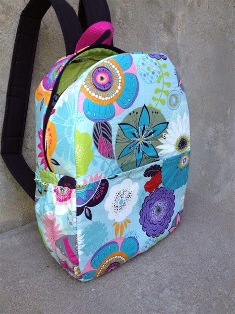A Colorful Backpack Sitting On The Ground Next To A Cement Wall With A