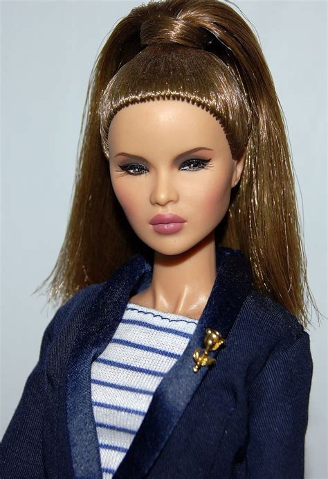 A Close Up Of A Doll Wearing A Blue Jacket And White Shirt With Gold Trim