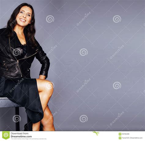Pretty Brunette Confident Mature Woman Sitting On Chair In Studi Stock