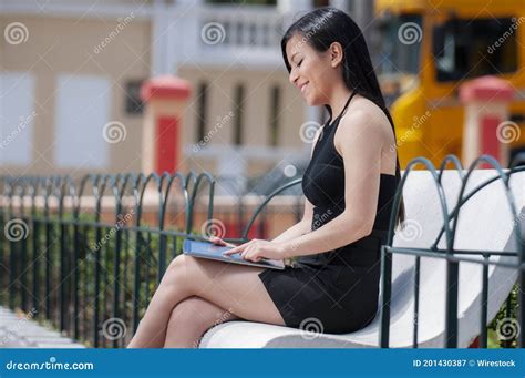Beautiful Hispanic Female Sitting On A Bench And Working With Her