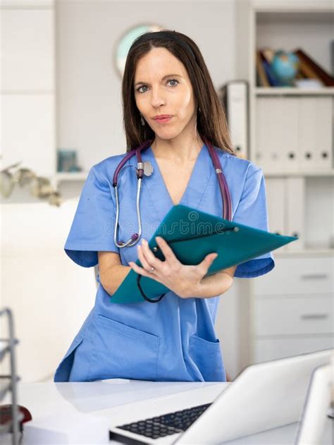 Woman Doctor Holding Paper Folder And Looking At Camera Stock Image