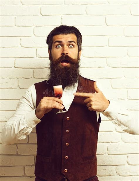 handsome bearded man with long beard and mustache has stylish hair on surprised face holding